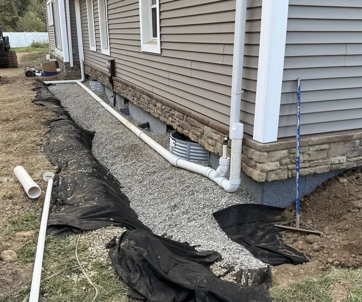 New downspout and foundation drainage system with gravel bed and cleanouts
